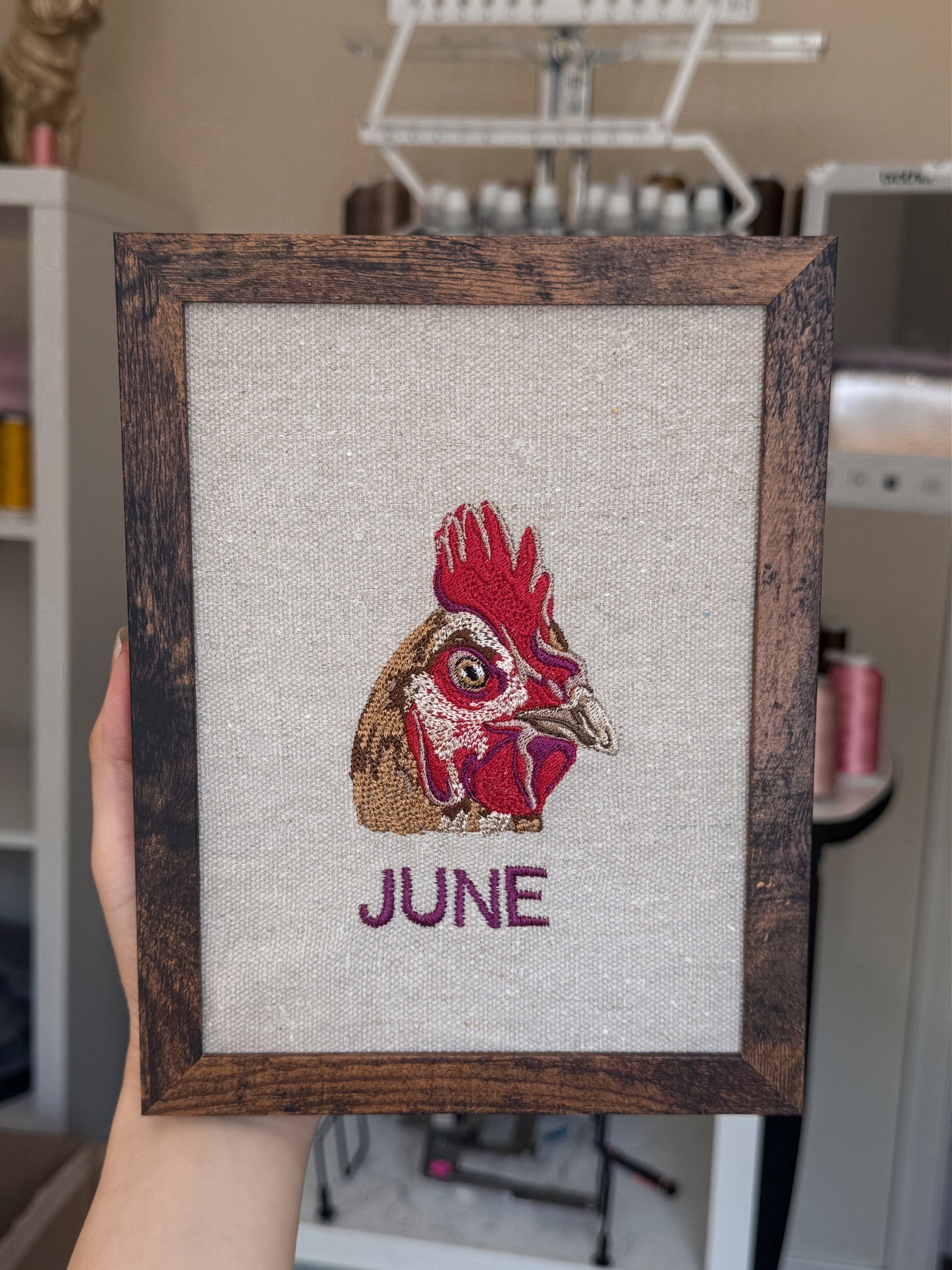 Framed embroidered chicken named June in an artistic studio setting