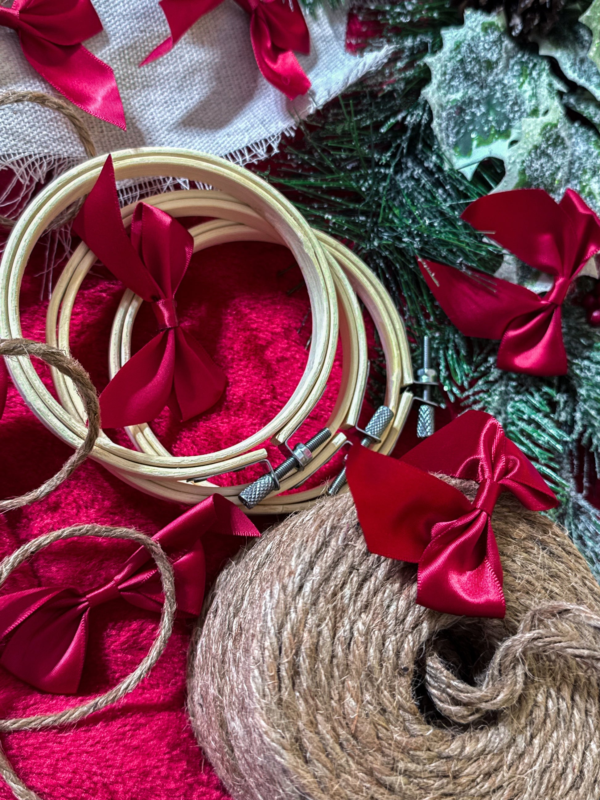 Decorative hoop with red ribbons and jute twine on a textured surface