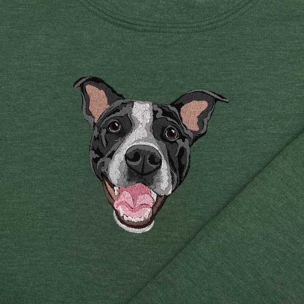 A green crewneck sweatshirt with a embroidered depiction of a custom dog's face in a happy expression.