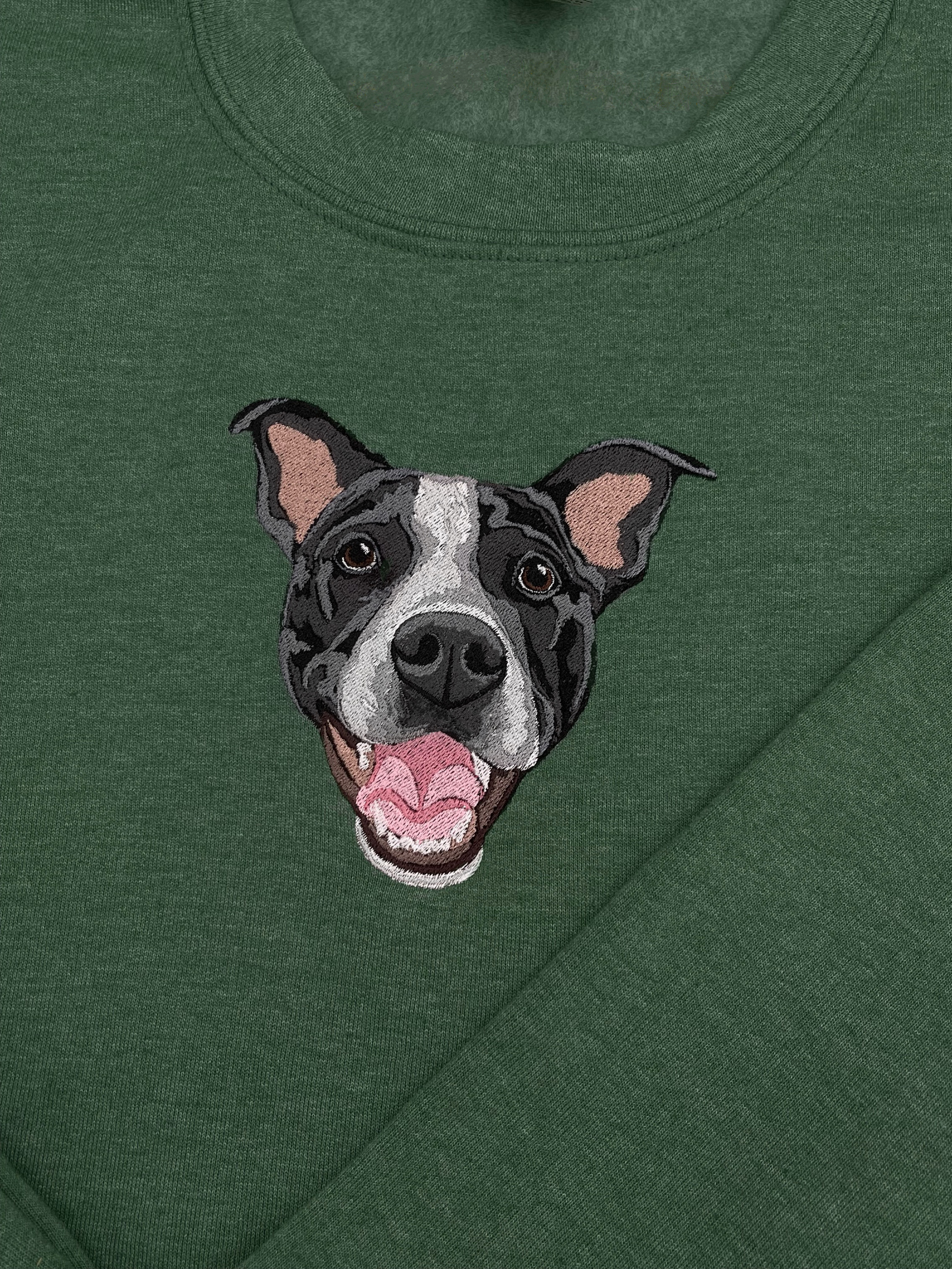 A green crewneck sweatshirt with a embroidered depiction of a custom dog's face in a happy expression.