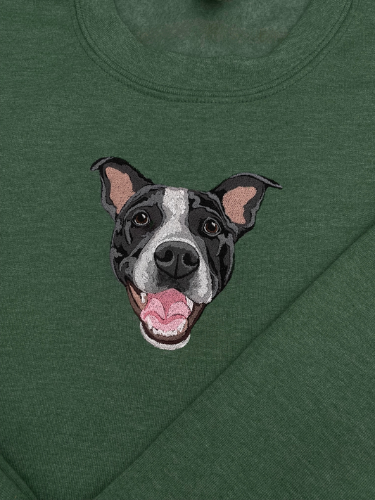 A green crewneck sweatshirt with a embroidered depiction of a custom dog's face in a happy expression.