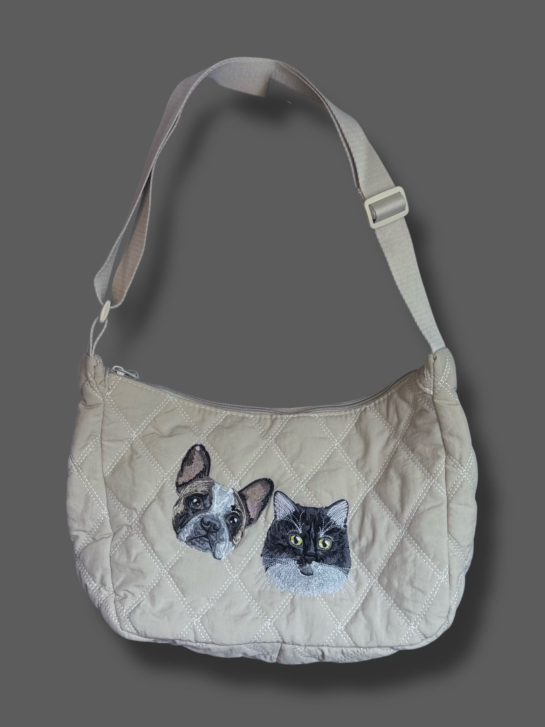 Beige quilted handbag with cat and dog appliqués on a gray background