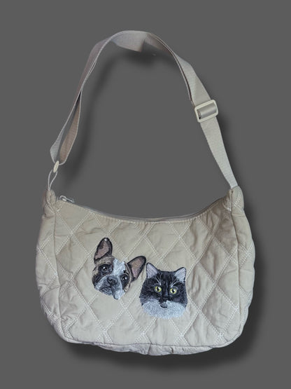 Beige quilted handbag with cat and dog appliqués on a gray background