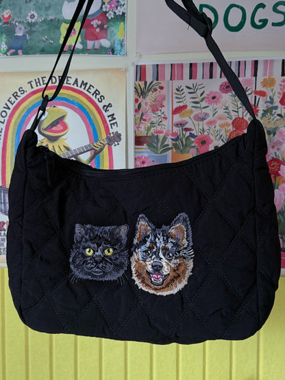 Black pet carrier with embroidered cat and dog design against a colorful wall.