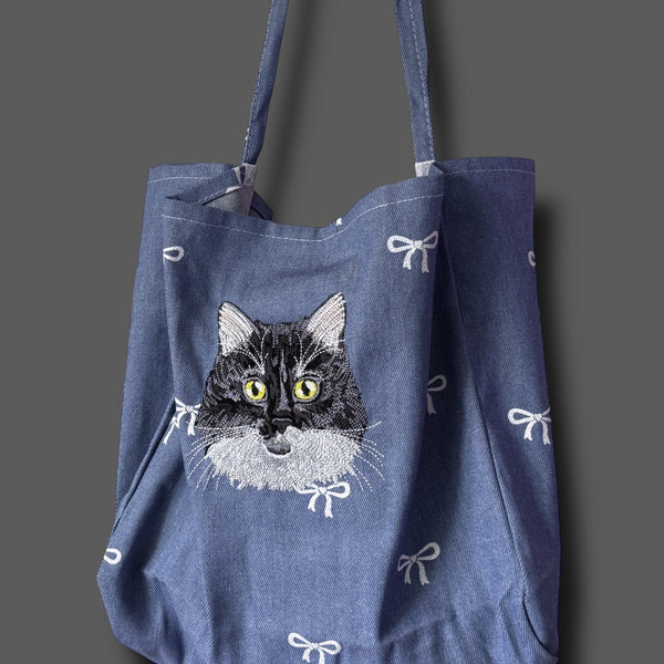 Blue tote bag with a cat illustration on a gray background