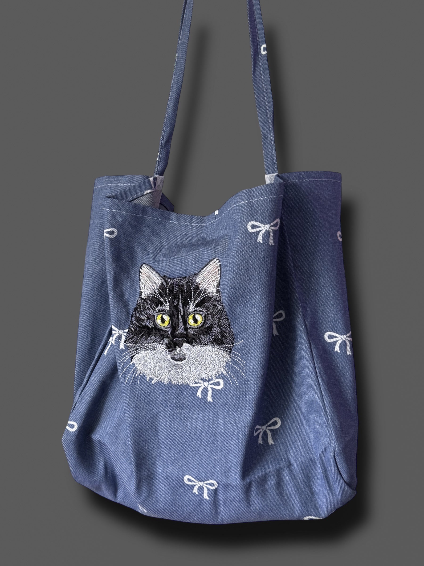 Blue tote bag with a cat illustration on a gray background