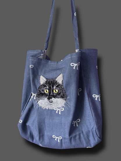 Blue tote bag with a cat illustration on a gray background