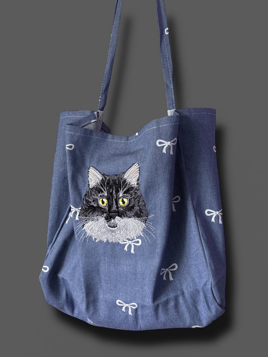 Blue tote bag with a cat illustration on a gray background