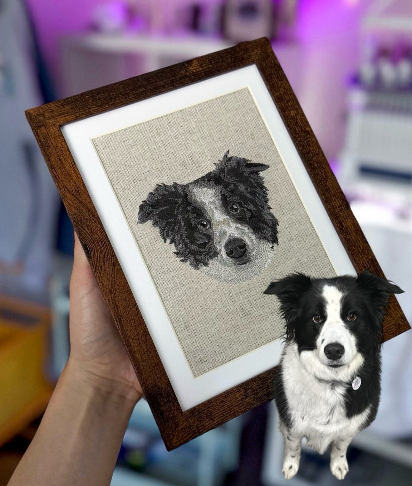Framed embroidered portrait of a dog held by a person next to a real black and white dog.