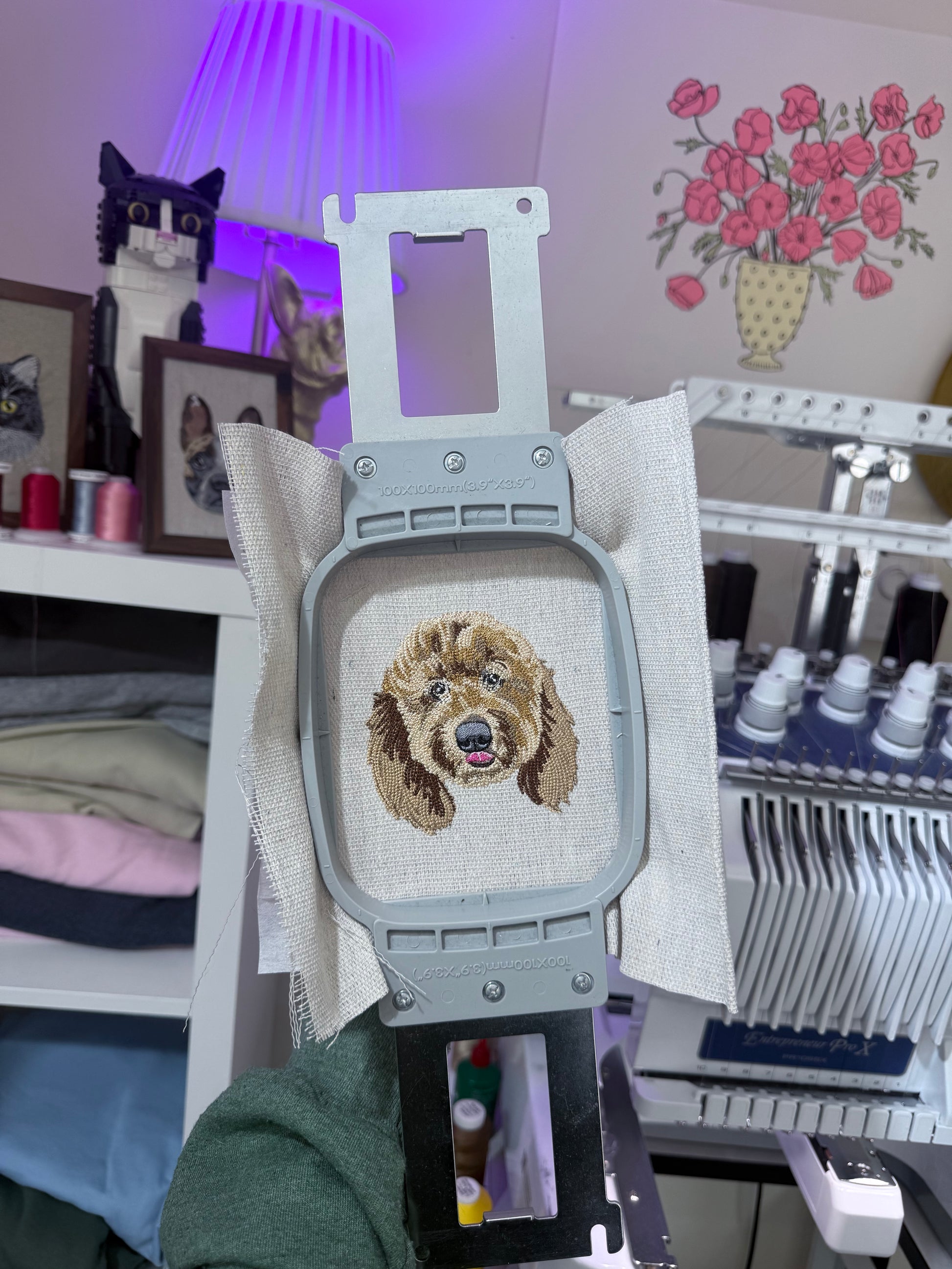 Embroidery of a dogs face on canvas fabric with artistic and cream decorative elements.