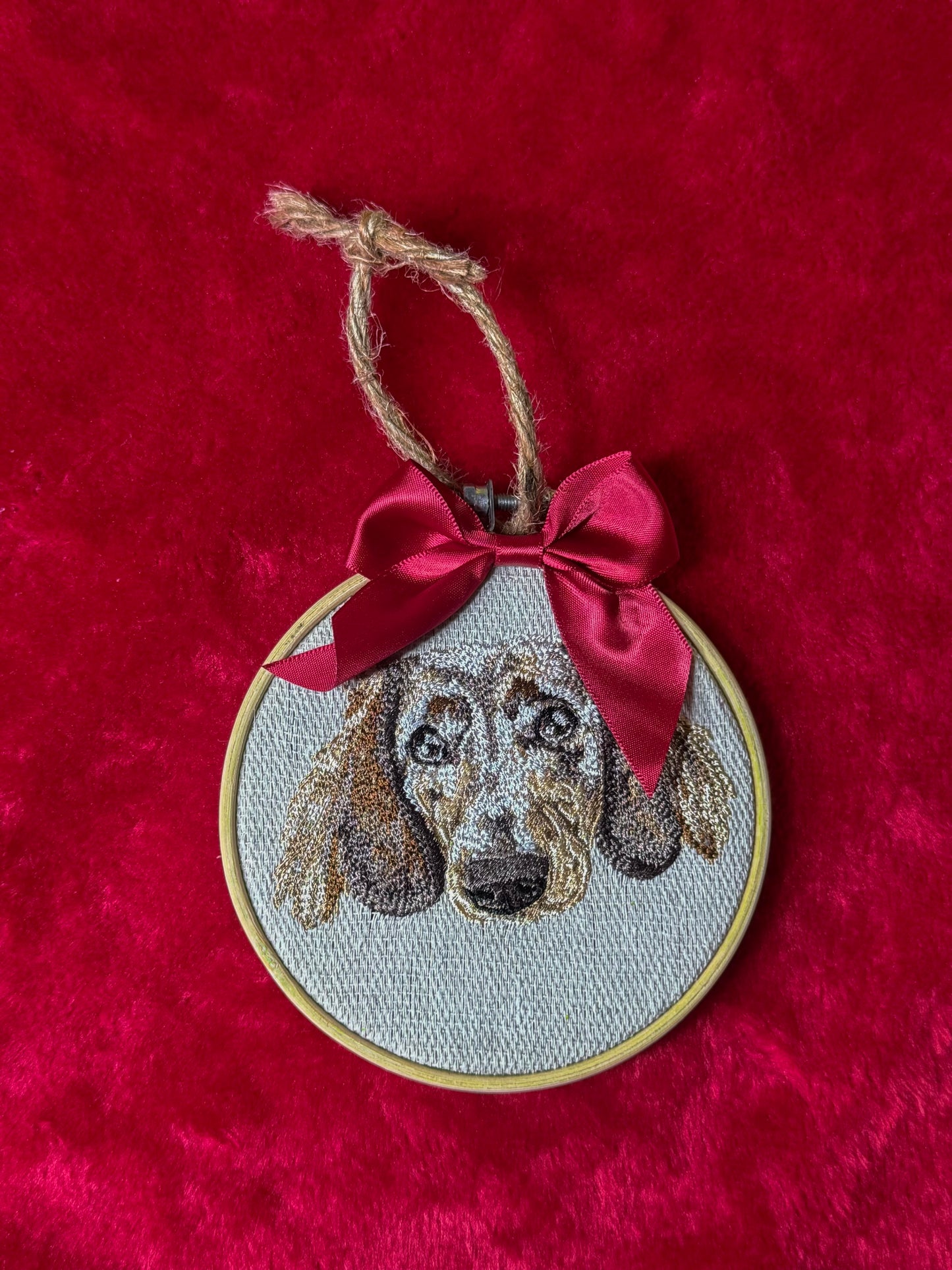 Embroidered dog portrait in a hoop with a red ribbon on a red background