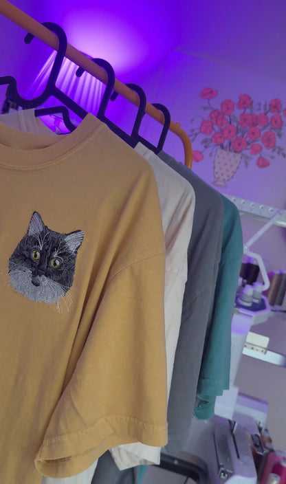 Rack of custom pet embroidered tshirts in a purple lit room