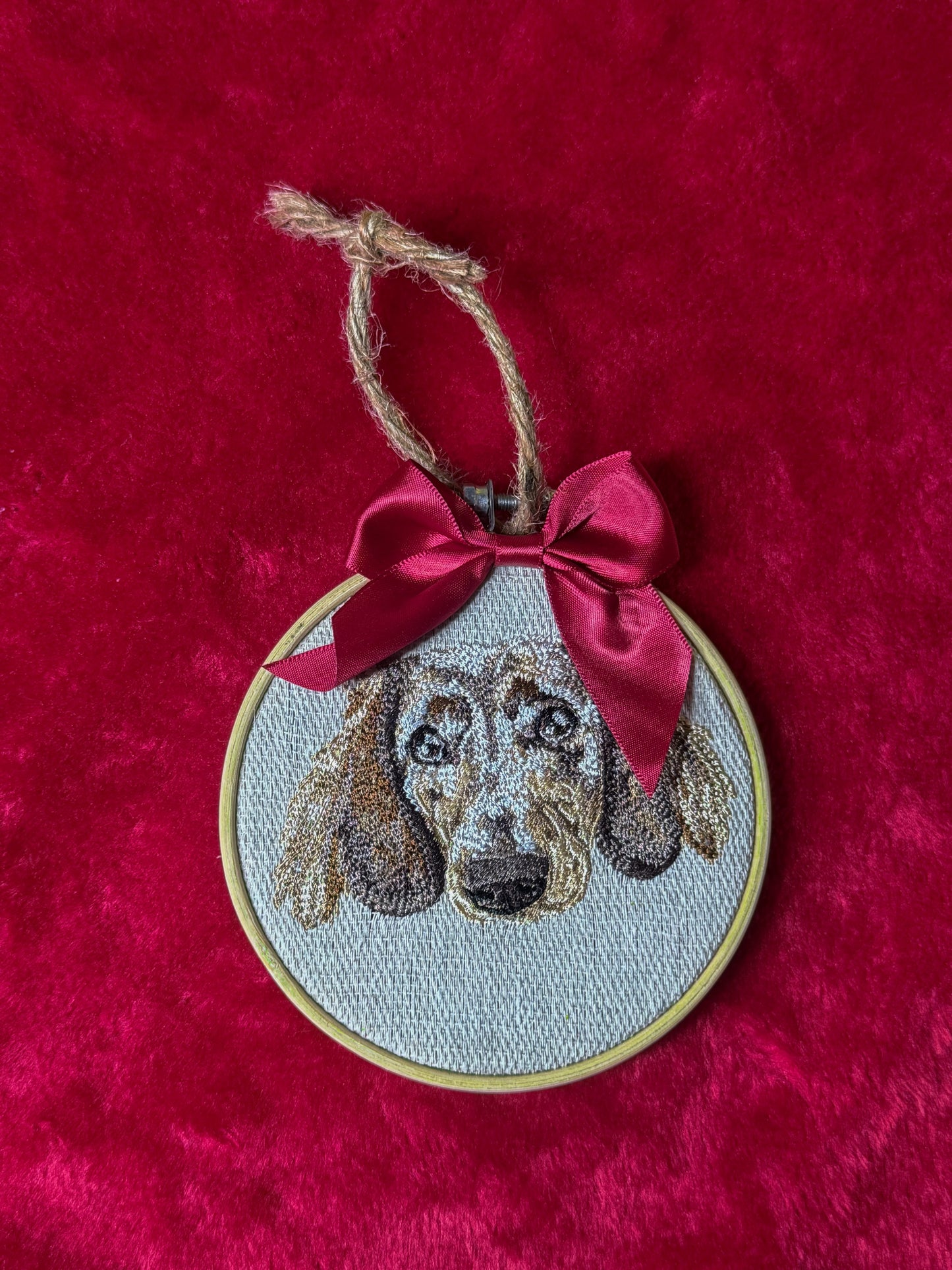 Embroidered dog portrait in a hoop with a red bow on a red background