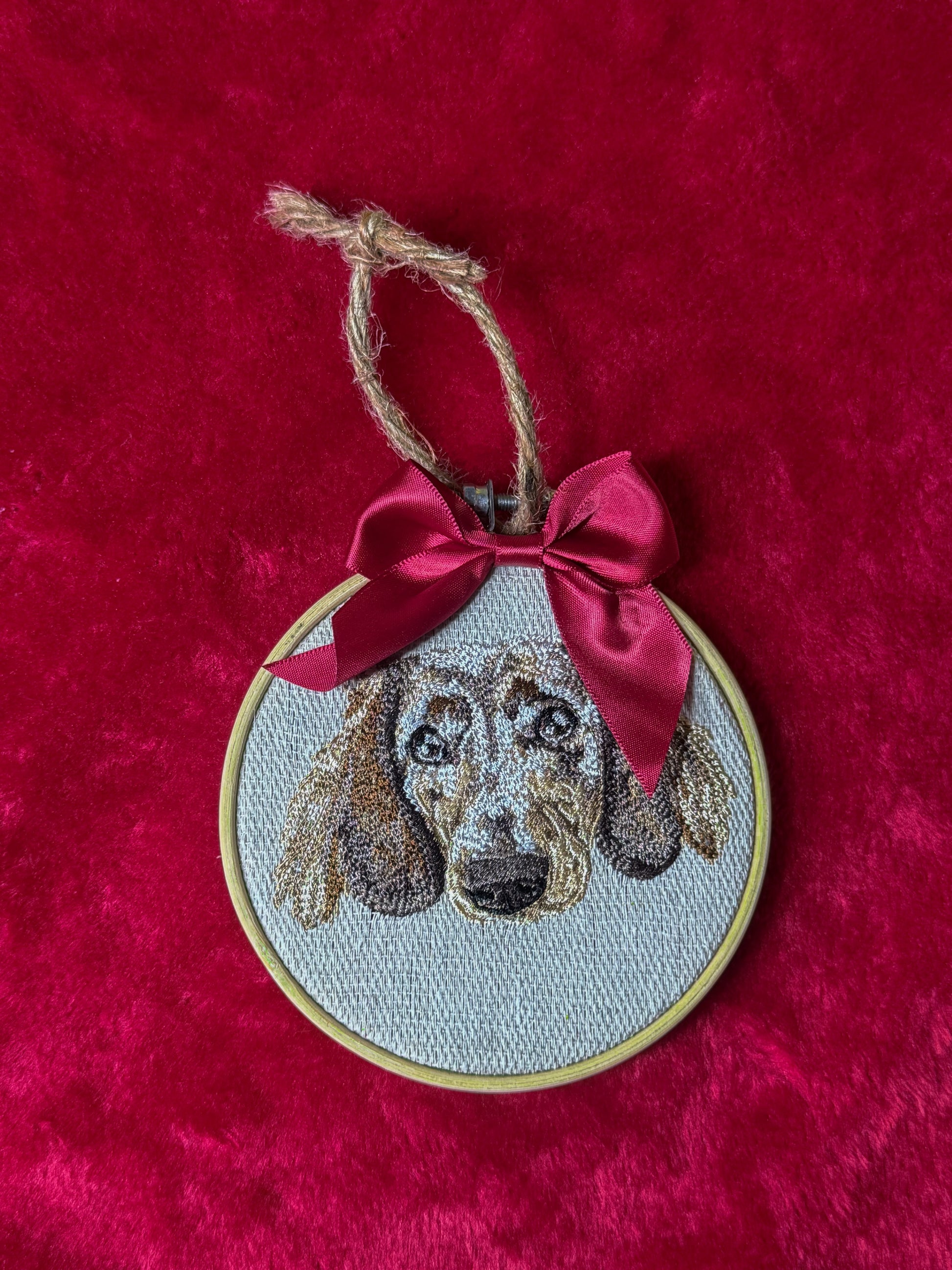 Embroidered dog portrait in a hoop with a red bow on a red background
